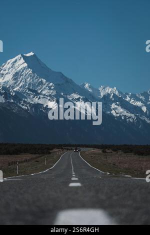 La montagna più alta della nuova Zelanda con una cima innevata. Con i suoi 3724 m, Aoraki / Monte Cook è la vetta più alta delle Alpi meridionali e delle Alpi neozelandesi. La strada SH8 corre in primo piano e conduce verso le montagne con segni distintivi. Foto Stock