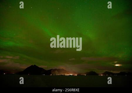 Naviga lungo la costa della Norvegia scintillante cielo notturno verde sopra la catena montuosa del Lofoten Foto Stock