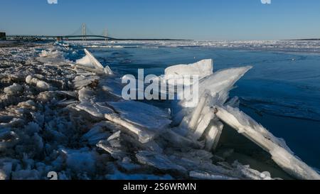 Piatti di ghiaccio e ghiaccio galleggiante sul lago Huron vicino alla linea costiera del Michigan vicino al ponte di Mackinaw. Foto Stock