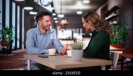 Ridendo uomo e donna seduti al caffè bevendo caffè e parlando Foto Stock
