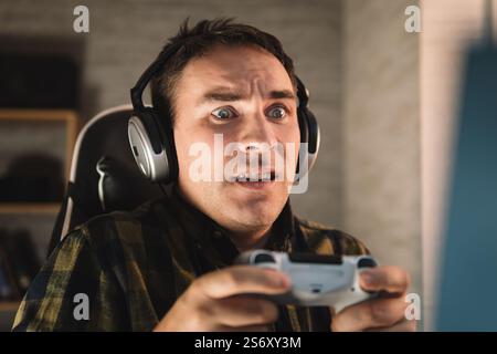 Primo piano di un giovane che gioca. Un appassionante uomo sportivo che si sente felice e allegro, si diverte a utilizzare la console di gioco joystick del Foto Stock