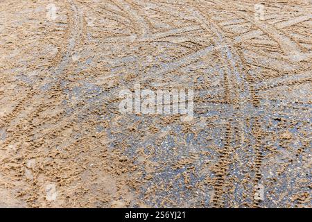 Le piste di attraversamento degli pneumatici attraversano strade bagnate e innevate, struttura di fondo per il trasporto invernale Foto Stock