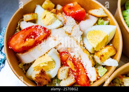 Una ciotola fresca di insalata di pollo con pollo alla griglia, avocado, pomodori, uova sode e crostini croccanti, prepariamo un pranzo nutriente Foto Stock