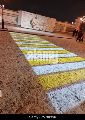Attraversamento pedonale proiettato; strisce luminose bianche e gialle sulla neve; proiezione di luce; zebra Foto Stock