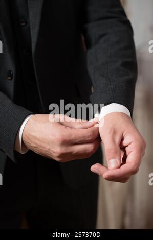 Uomo che si adegua ai bracciali, dettaglio di una tuta formale. Stile nitido ed elegante. Foto Stock