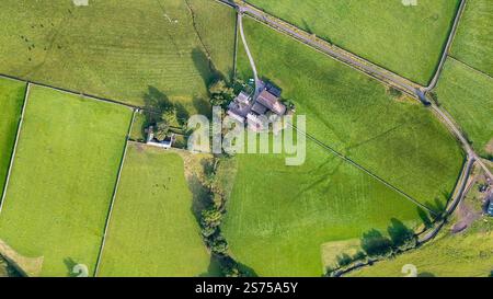 Vista aerea dall'alto verso il basso della fattoria rurale britannica con edifici in pietra circondati da campi verdi northumberland, tassa di successione britannica Foto Stock