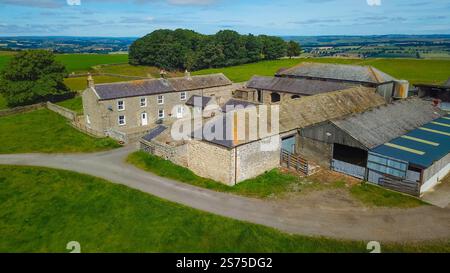 Vista aerea del cortile rurale britannico con edifici in pietra e fienili circondati da lussureggianti campi verdi, tassa di successione del regno unito del northumberland Foto Stock