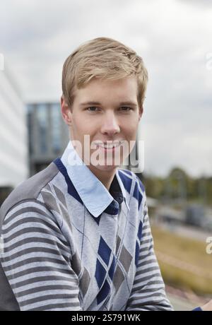 Sorridente giovane e bello biondo in piedi all'aperto, Belgio, Europa Foto Stock