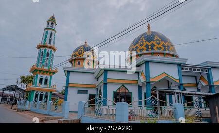 Una moschea colorata con un alto minareto e due cupole, caratterizzata da intricati motivi geometrici, posta contro un cielo nuvoloso Foto Stock