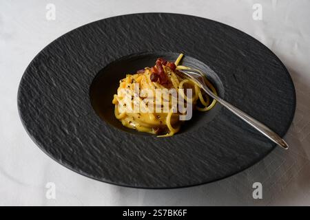 Spaghetti alla carbonara, pasta italiana in stile romano con salsa di uova e formaggi, condita con pancetta Guanciale Foto Stock
