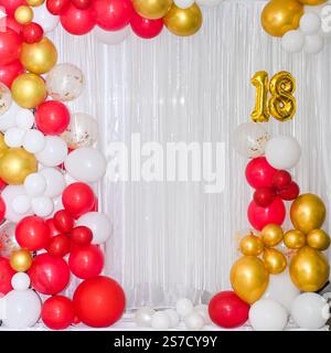 Palloncini colorati luminosi su sfondo bianco per un compleanno di diciotto anni. Uno striscione natalizio con il numero 18. Foto Stock