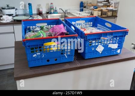 Shopping online e consegna di generi alimentari dal supermercato Tesco con scatole blu piene di cibo senza sacchetti di plastica su un'isola in una cucina britannica Foto Stock