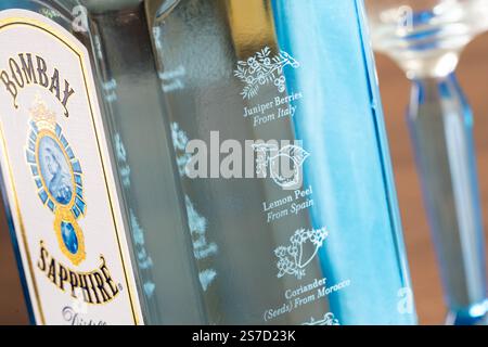 Iconica bottiglia blu di gin Bombay Sapphire con dieci ingredienti botanici e la loro origine incisa nel bicchiere, tra cui bacche di ginepro provenienti dall'Italia Foto Stock