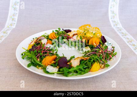 Un'insalata splendidamente allestita presenta verdure fresche, varie verdure colorate e condimenti decorativi su un piatto bianco, mettendo in risalto le arti culinarie Foto Stock