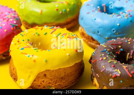 Ciambelle colorate smaltate su sfondo giallo, primo piano Foto Stock