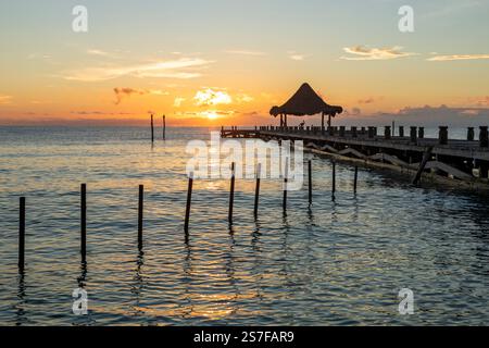 Messico, Puerto Morelos, molo con palapa all'alba su una spiaggia tranquilla. Foto Stock
