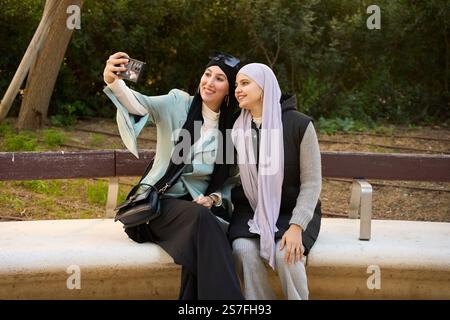 Due donne musulmane che fanno un selfie nel parco Foto Stock