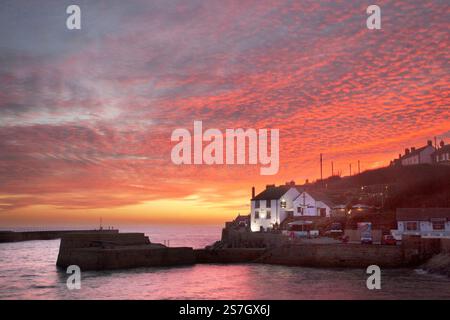 Un ardente tramonto di sgombri sulla nave Inn e riflesso nel mare a Porthleven Harbour, Cornovaglia Foto Stock