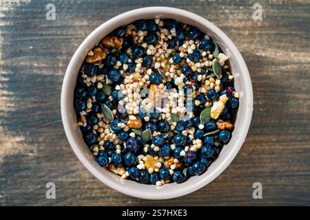 Grano saraceno verde biologico fatto in casa con mirtilli, noci, semi di zucca e miele in una ciotola di ceramica su sfondo di legno. Pausa vegetariana sana Foto Stock