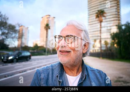 Elegante anziano che cammina in città al tramonto, godendo della pensione Foto Stock