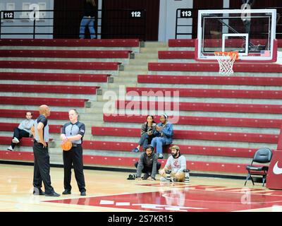 Due ufficiali di basket della NCAA in uniforme aspettano sul campo vicino a un cestino e a un tabellone durante il timeout di una partita. Foto Stock