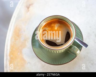 Caffè nero caldo in tazza verde e piattino su tavolo in marmo bianco. Vista dall'alto. Foto Stock