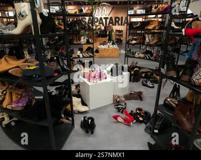 Negozio di scarpe da donna in vendita, tanti stivali e tacchi alti non ordinati sugli scaffali e sul pavimento Foto Stock