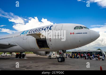 I passeggeri salgono a bordo di un volo Air Transat dall'asfalto all'aeroporto di Port-au-Prince. Un momento di resilienza e speranza per i viaggiatori. Foto Stock