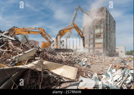 Cantiere edile. Pile di rifiuti di cemento armato e rottami metallici. 3 escavatori LIEBHERR con frantumatore e benna. Foto Stock