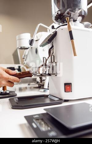 Barista che prepara caffè selettivo da chicchi freschi. Il macinacaffè macina i chicchi di caffè freschi in un portafiltro per la macchina espresso. Foto Stock