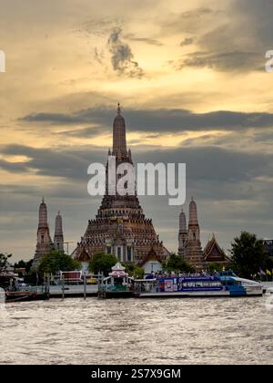 Il maestoso Wat Arun, noto anche come il Tempio dell'Alba, si erge alto contro un suggestivo cielo al tramonto a Bangkok, Thailandia. Il design intricato del centro Foto Stock