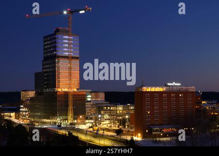 Stoccolma, Svezia Januari 4th, 2025. Moderno grattacielo con facciata in vetro con una gru sullo sfondo del cielo limpido, che costruisce Sickla Central Off Foto Stock