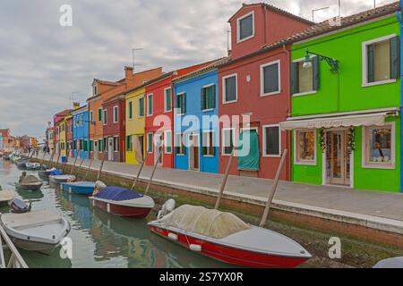 Venezia, Italia - 10 gennaio 2017: Barche ormeggiate al canale dell'acqua e case colorate in fila all'isola di Burano, viaggio invernale di un giorno. Foto Stock