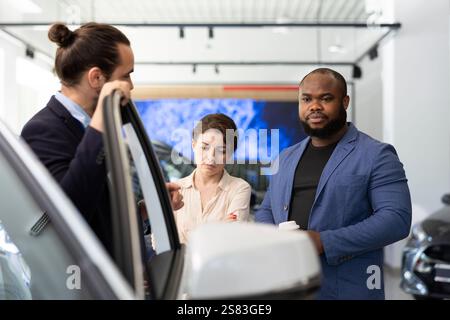 Il venditore della concessionaria invita i clienti a effettuare test di guida per dimostrare le capacità del veicolo. Il dipendente dello showroom suggerisce ai clienti attrezzature opzionali per l'acquisto Foto Stock
