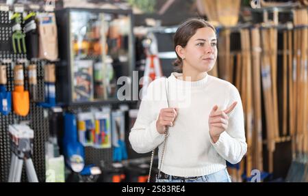 Giovane donna che sceglie gli attrezzi per il giardino Foto Stock