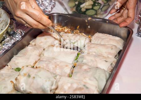 Una mano con un cucchiaio per servire involtini di cavolo ripieni appena sfornati, ripieni di riso e verdure Foto Stock
