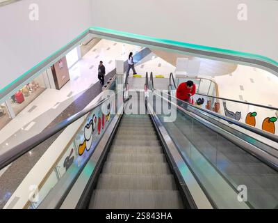 Century Place, Shenzhen, Cina - 20 gennaio 2025: Vista ad alto angolo di una scala mobile in un moderno centro commerciale. Le persone sono viste salire e descendi Foto Stock