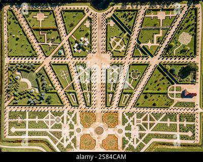 Vista aerea di un giardino formale caratterizzato da sentieri geometrici, una fontana centrale, siepi, aiuole di fiori, una struttura simile a un labirinto e un edificio dal tetto rosso Foto Stock