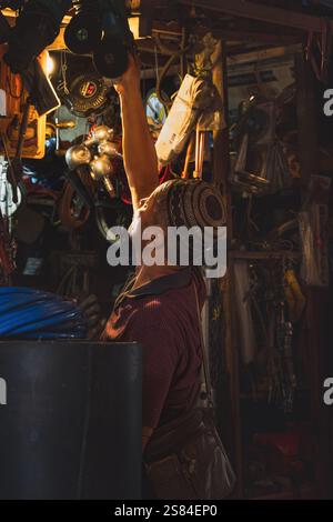Balikpapan, Indonesia - 25 dicembre 2024. Il vecchio sta installando i suoi vecchi utensili industriali, come smerigliatrici e seghe, al suo mercato delle pulci. Foto Stock