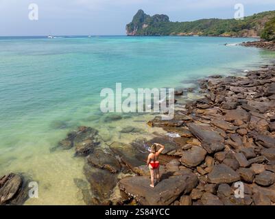 Vista aerea di una giovane donna con un costume da bagno in piedi sulle rocce costiere di Koh Phi Phi Don, Thailandia Foto Stock