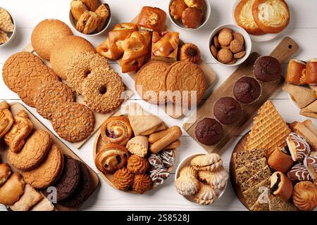 Varietà di prodotti da forno esposti su superfici in legno, tra cui biscotti, pasticcini e dolci per una piacevole riunione Foto Stock