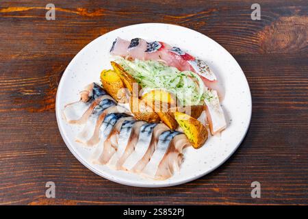 Un piatto di pesce splendidamente organizzato presenta vari tipi di pesce fresco, accompagnato da spicchi di patate arrosto e un lato di insalata croccante. Perfetto f Foto Stock