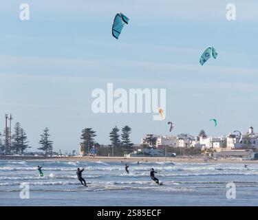 Kite Surfers che scivolano sulle onde del mare con la storica Medina alle spalle nella città di Essaouira, in Marocco. 20 gennaio 2025 Foto Stock
