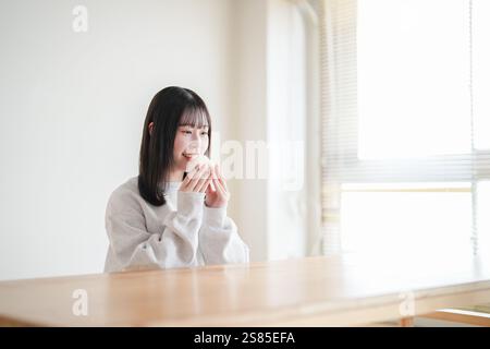 La giovane donna giapponese di vent'anni siede nella stanza del tatami e ama la palla di riso fatta solo di riso bianco. Foto Stock