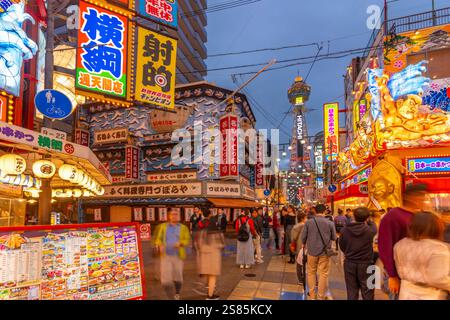 Vista della Torre Tsutenkaku e dei ristoranti con luci al neon al crepuscolo nell'area di Shinsekai, Osaka, Honshu, Giappone Foto Stock