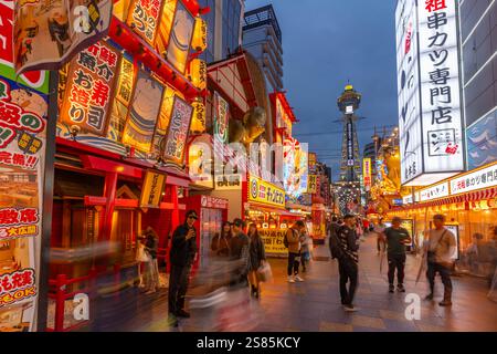 Vista della Torre Tsutenkaku e dei ristoranti con luci al neon al crepuscolo nell'area di Shinsekai, Osaka, Honshu, Giappone Foto Stock