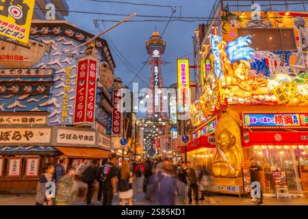 Vista della Torre Tsutenkaku e dei ristoranti con luci al neon al crepuscolo nell'area di Shinsekai, Osaka, Honshu, Giappone Foto Stock