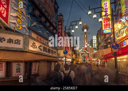 Vista della Torre Tsutenkaku e dei ristoranti con luci al neon di notte nell'area di Shinsekai, Osaka, Honshu, Giappone Foto Stock