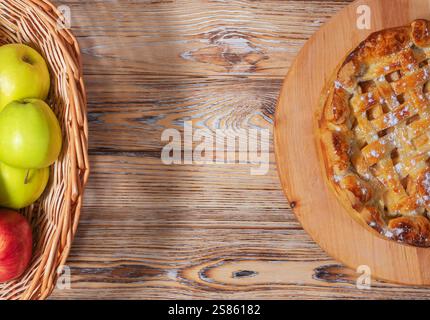 Mele fresche in un cestino e torta di mele fatta in casa su un tavolo di legno Foto Stock