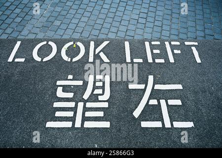 Guarda a sinistra, Warnhinweis auf dem Asphalt, Hong Kong, Volksrepublik China *** Guarda a sinistra, cartello di avvertimento sull'asfalto, Hong Kong, Repubblica popolare cinese Foto Stock